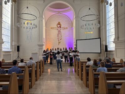 Ein Chor aus 15 Personen singt in der Kirche, Frontalansicht.
